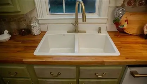 Вид на чугунную раковину с белой эмалью в столешнице мясного блока