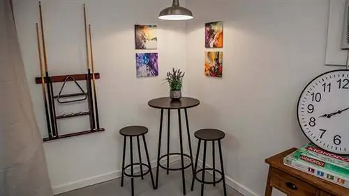 Бистро в углу комнаты с картинами на стенах и стойкой для клюшек для бильярда.