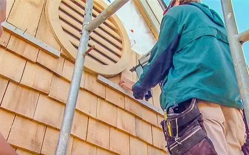 Мужчина устанавливает сайдинг в доме