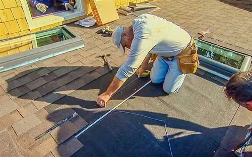 Мужчина устанавливает крышу из битумной черепицы