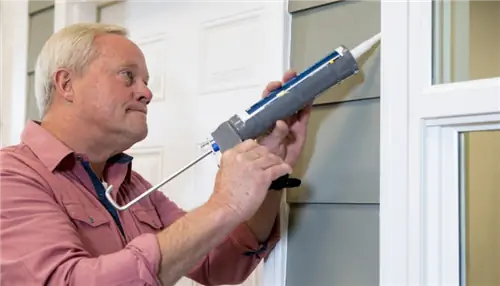 На этом изображении Дэнни использует герметик, чтобы заделать щель в окне.