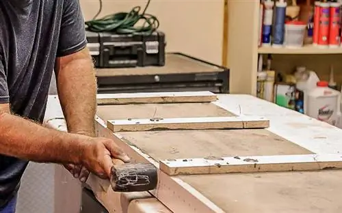 Мужчина постукивает по своей бетонной форме резиновым молотком