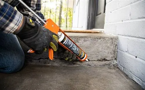 Рука в перчатке наносит герметик Quikrete Advanced Polymer Concrete Crack Sealant с помощью пистолета для герметика