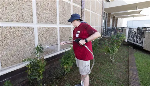 На этом изображении изображен мужчина, моющий под давлением стену сувенирного магазина. Здание пористое.