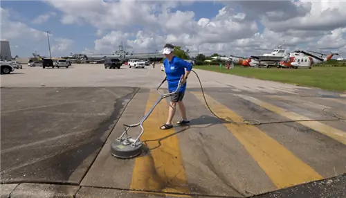 На этом изображении обувь человека, использующего круглую мойку высокого давления для очистки бетона.