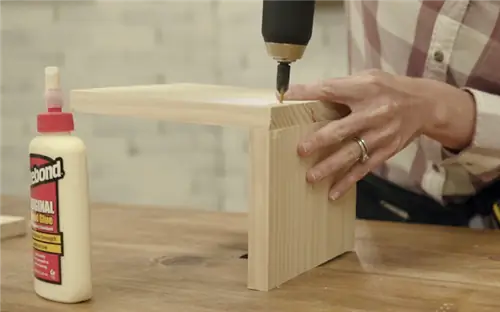 Сверление пилотного отверстия в подлокотнике дивана рядом с бутылкой клея Titebond Original Wood Glue.