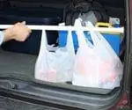 Пакеты с продуктами, закрепленные в задней части автомобиля с помощью штанги для занавески для душа.
