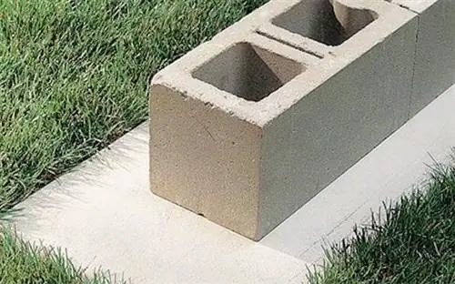 Установка нижнего шлакоблока бетонной стены