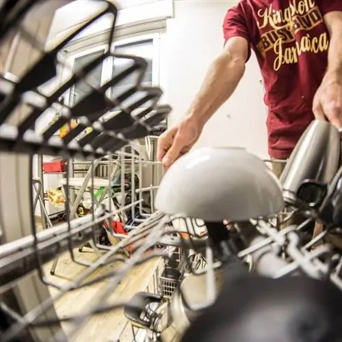 мужчина вытаскивает загруженную полку для посудомоечной машины