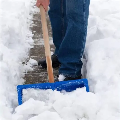 Владелец недвижимости убирает снег синей лопатой