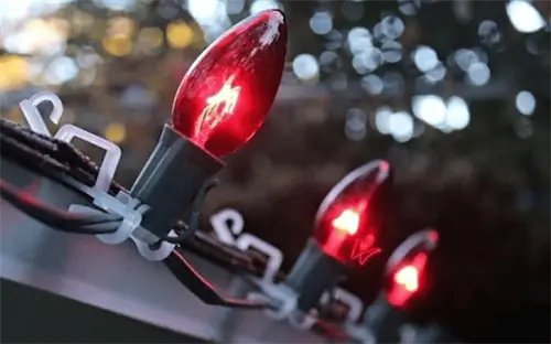 зажимы, прикрепляющие красные праздничные огни к черепице крыши