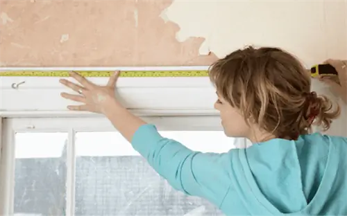 человек измеряет оконную раму рулеткой