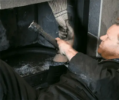 Специалист по дымоходам осматривает и чистит камин