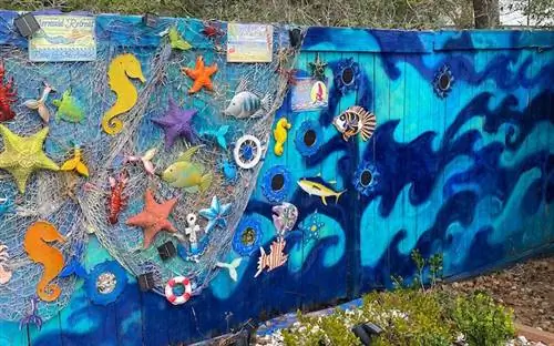 Забор расписан подводными голубыми волнами с морскими звездами и рыбным декором