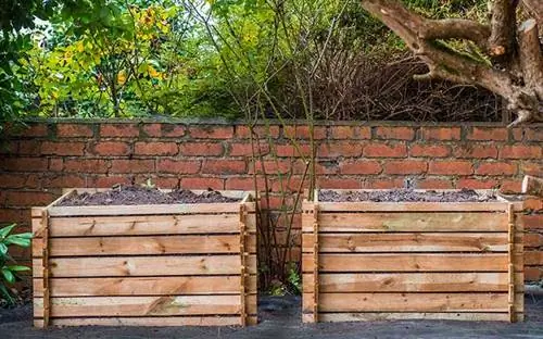 Ящик для древесного компоста возле кирпичного забора на заднем дворе.