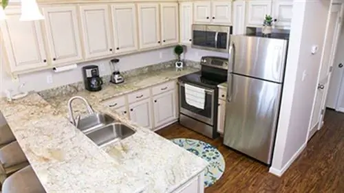 Отремонтированная кухня с обновленными шкафами, гранитными столешницами, виниловыми полами и новой бытовой техникой.