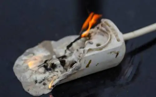 Удлинитель с расплавленным пластиком, вспыхнувшим огнем и дымом, чтобы проиллюстрировать рыбный запах в доме.