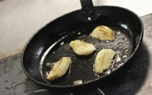 Лук жарится на чугунной сковороде