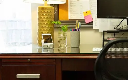 Общий план стола из красного дерева с бетонной ручкой для ящика, бетонной подставкой для iPhone и бетонной чашкой для ручек.