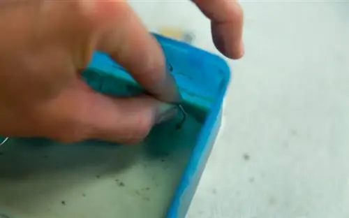 Крупный план руки, вставляющей скрепку в первую заливку бетона.