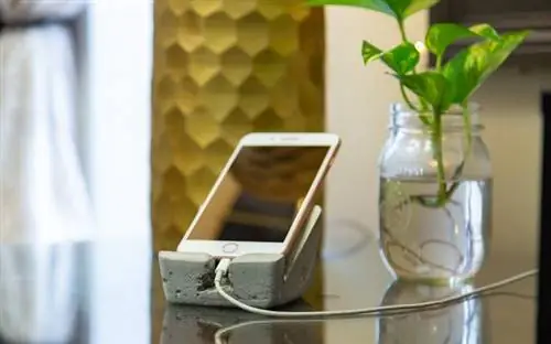 Крупный план офиса с бетонной подставкой для iPhone на рабочем столе из красного дерева