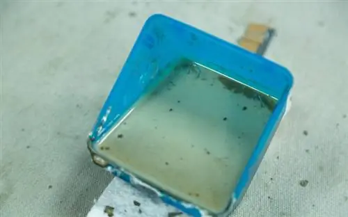 Крупный план пластиковой бетонной формы, заполненной бетонной смесью, и две скрепки для поддержки