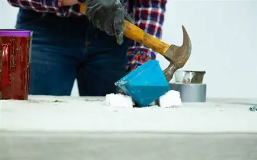 Рука в перчатке приклеивает пластиковую форму резиновым молотком.