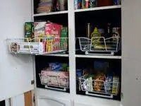Выдвижные проволочные корзины, вмонтированные в кухонные шкафы.