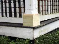 Новое неокрашенное дерево на основании колонны крыльца.