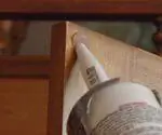 Нанесение силиконового герметика на дверцу шкафа. Нанесение силиконового герметика на дверцу шкафа.