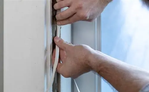 Руки наносят пенопластовый уплотнитель Duck Brand на окно