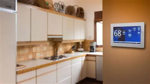 Этот интеллектуальный термостат, установленный на стене на кухне, работает с геотермальным тепловым насосом для обеспечения тепла.