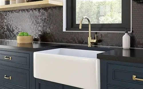 Синие шкафы с золотыми ручками на современной кухне с черным фартуком