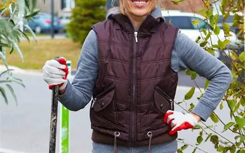 Женщина, стоящая с граблями в удобных перчатках для работы по дому