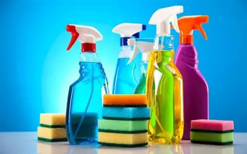 Средства для чистки бутылок с распылителем и губки на синем фоне Средства для чистки бутылок с распылителем и губки на синем фоне
