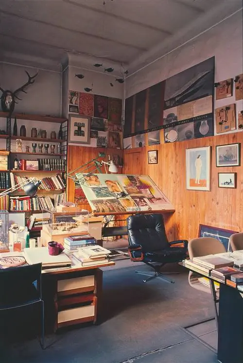 комната со столом кресло книжная полка с книгами и картинами