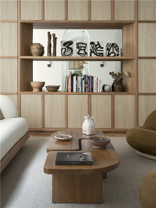 Напротив гостиной находится большой книжный шкаф из массива дуба и ткани ручной работы от Эммануэль Симон, который скрывает двери,…