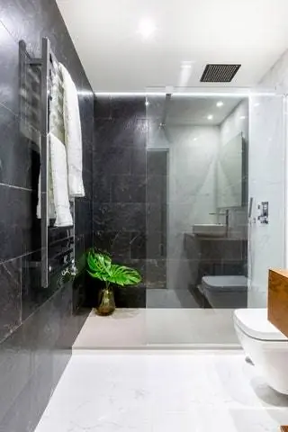 Керамические смесители и унитаз от Porcelanosa, изготовленная на заказ мебель из мореного дуба, а также изготовленное на заказ зеркало