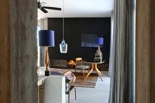 Черная стена и мебель середины века контрастируют с каменными стенами. Эстетика, которая преобладает над всем…