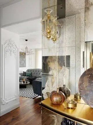 Фрагмент коридора и вид на гостиную. Стену украшает состаренное зеркало