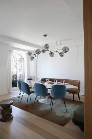 В столовой стулья от Gubi, стол от Eero Saarinen, люстра от Lindsey Adelman и скамейка…