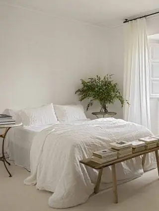 В главной спальне белое льняное постельное белье от Zara Home, шторы на заказ из такой же ткани, скамейка…