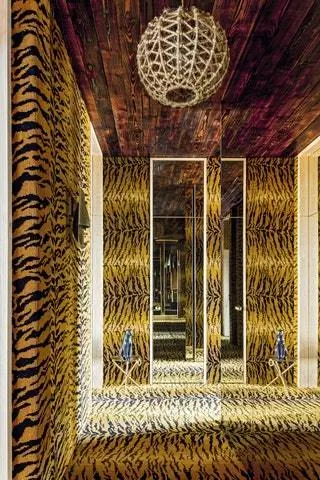 Коридор, ведущий в спальню, был устлан тигровым ковром. На заднем плане маленькие столики и старинный фарфор…