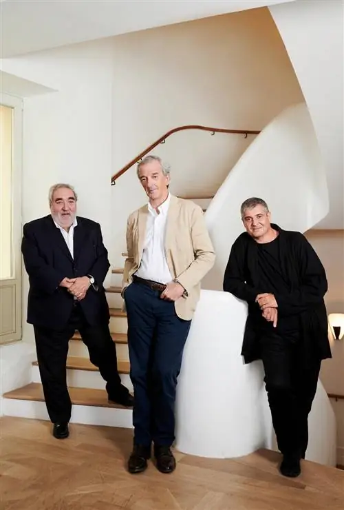 трое мужчин в костюмах позируют перед белой лестницей