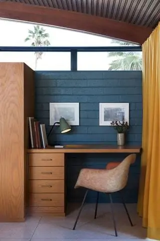 В маленьком рабочем уголке кресло Eames, деревянный стол и желтые шторы, разделяющие пространство