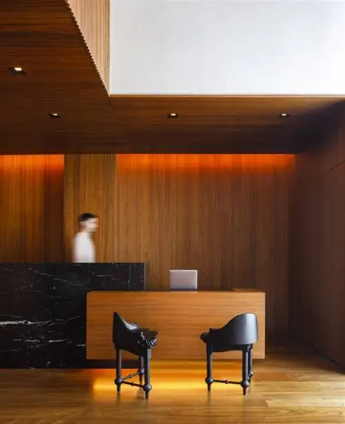 Лобби отеля встречает клиентов и горожан стойкой регистрации из черного мрамора и орехового дерева