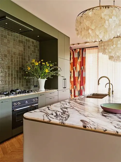 зеленая кухня с дизайнерскими светильниками из мраморного острова