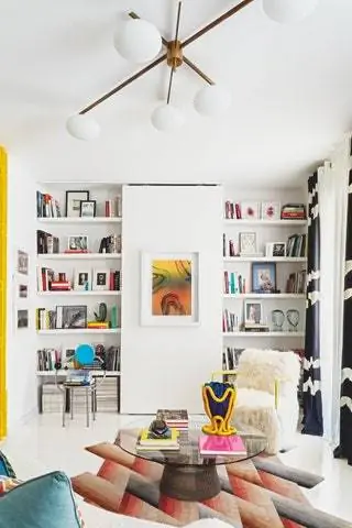 книжная полка с книгами белое кресло ковер