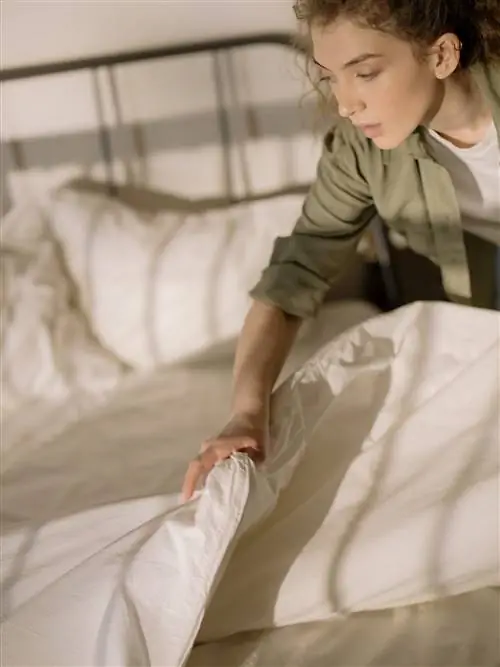 Женщина заправляет кровать