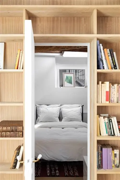 книжная полка с книгами и белая кровать